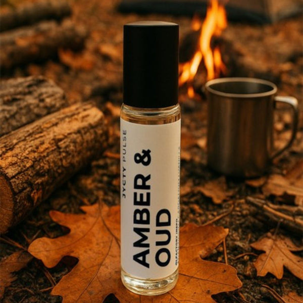 Bottle of long-lasting 'Amber & Oud' perfume oil by Jycty Pulse on a leafy ground with a campfire in the background.
