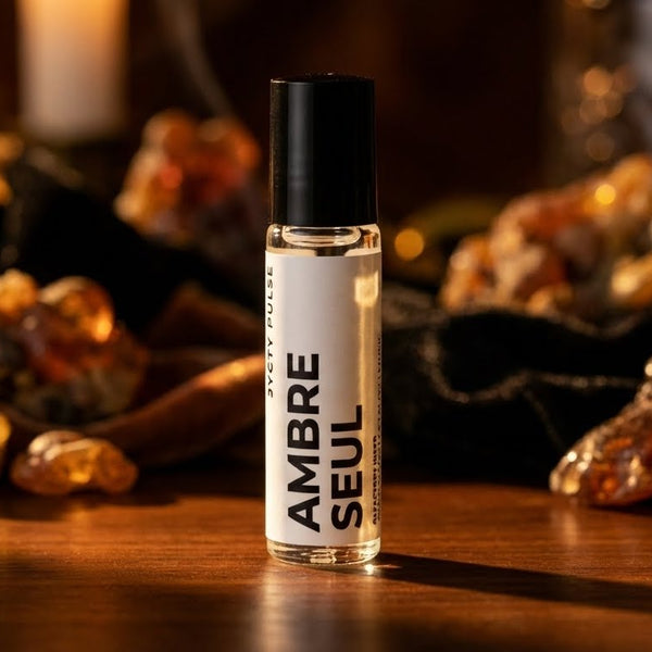 10ml Perfume oil bottle labeled 'Ambre Seul' on a wooden surface with amber-colored stones in the background.