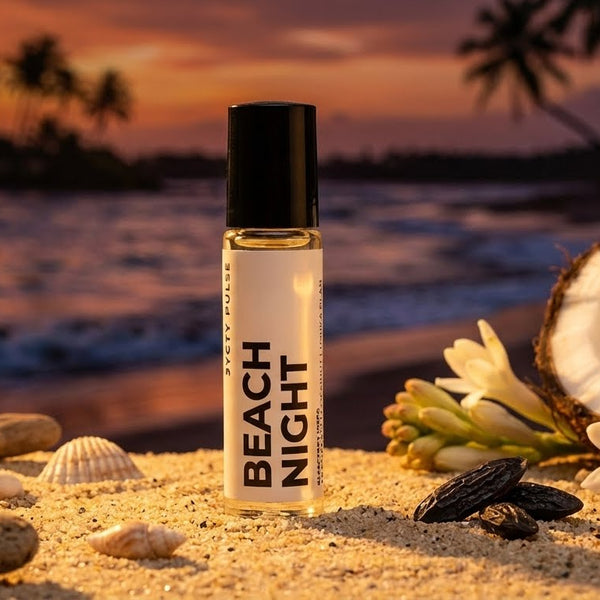 Rollerball labeled 'Beach Night' on a beach with sunset, coconuts, and flowers. Long Lasting vegan perfume oil