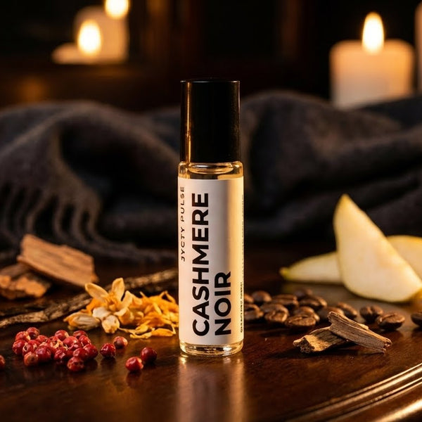 Cashmere Noir perfume oil on a wooden surface with candles and spices in the background. vegan and long lasting for women. also cruelty-free