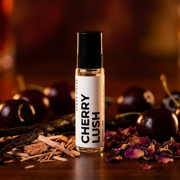 Cherry Lush perfume bottle with cherries, vanilla beans, and dried flowers on a wooden surface.