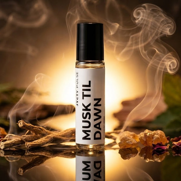 Perfume oil bottle labeled 'Musk Til Dawn' with smoke and natural elements on a reflective surface.