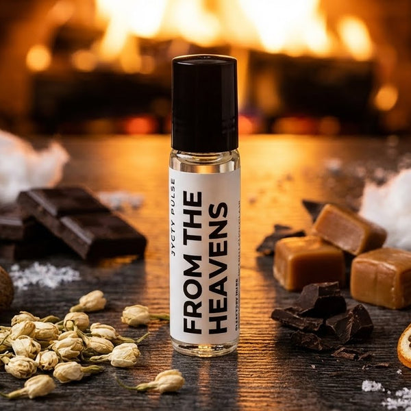 Roll-on perfume oil bottle labeled 'From the Heavens' on a wooden surface with various ingredients.