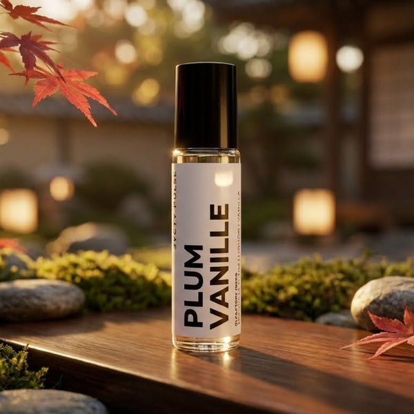 Plum Vanille perfume oil bottle on a wooden surface with a blurred garden background