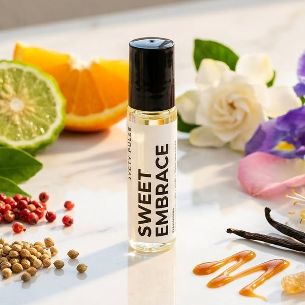 Roll-on bottle labeled 'Sweet Embrace' surrounded by fruits, flowers, and spices on a marble surface. long lasting and vegan perfume oil