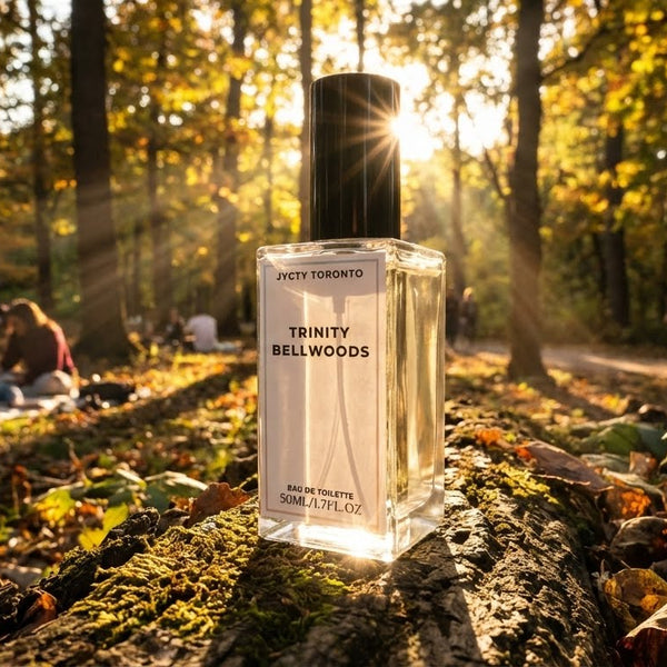 Perfume bottle labeled 'Trinity Bellwoods' in a forest setting with people sitting on logs. by JYCTY
