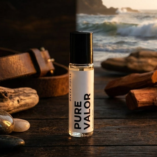 Roll-on bottle labeled 'PURE VALOR' on a wooden surface with driftwood and stones, sunset in the background.